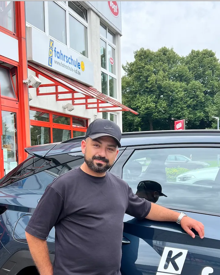Mehmet Güzel neben einem Fahrschulauto der Fahrschule KDL